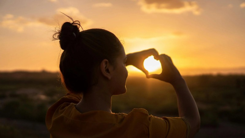 A silhouette of a young woman forming a heart shape at sunset in Kelâat M'Gouna, Morocco., tags: zelfzorgcentrum british - pexel